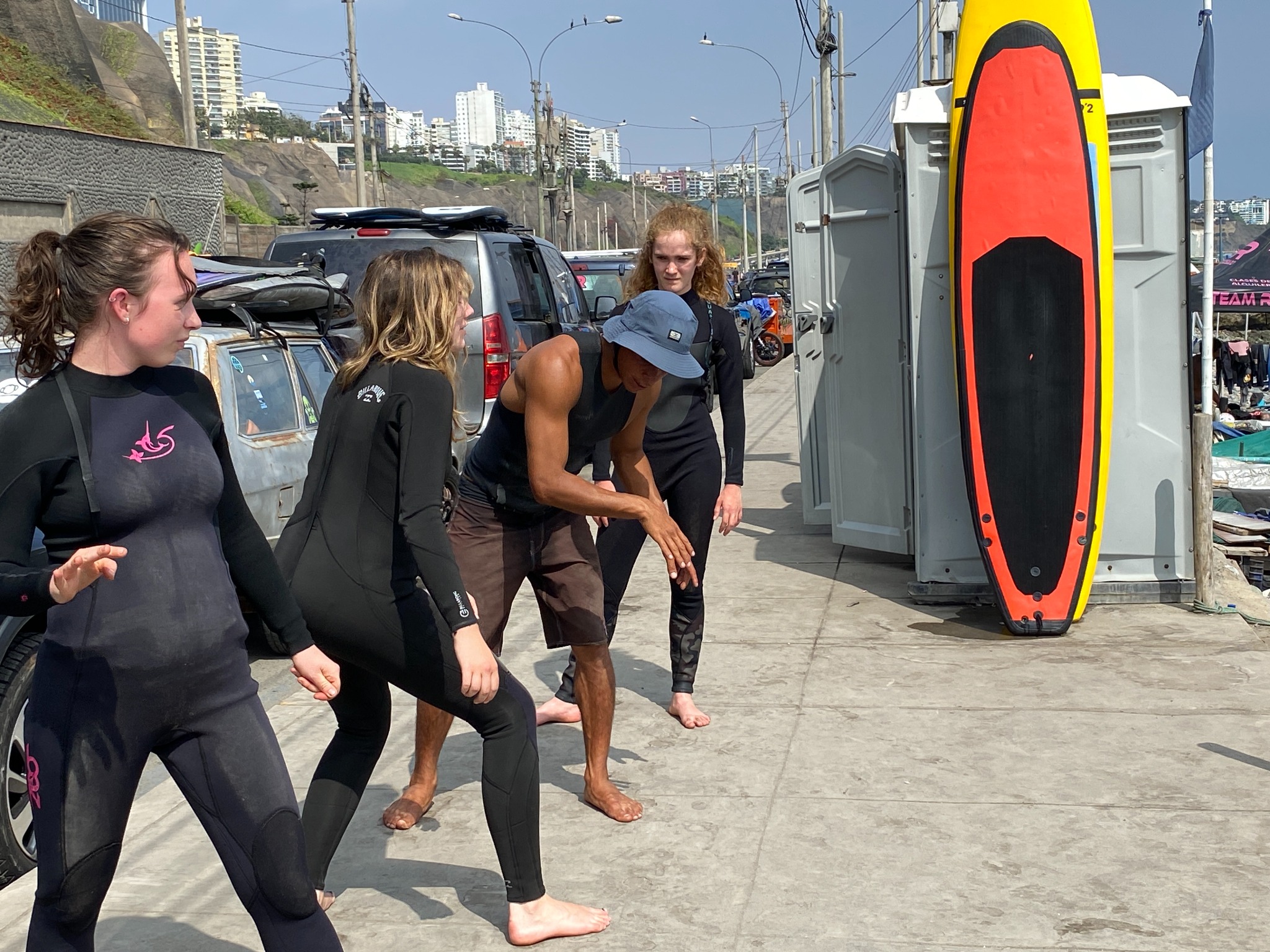 Instructor demonstrating a warm-up with students beside the surfboards